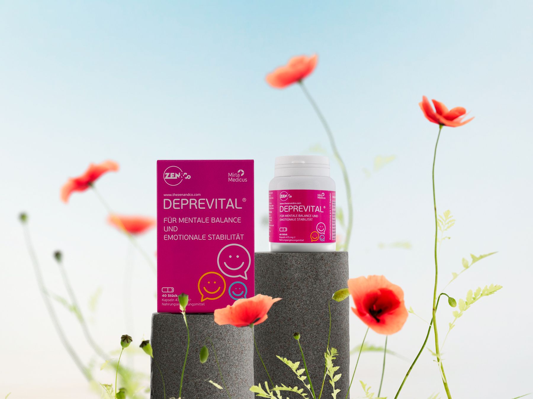 Deprevital Faltschachtel und Kapseldose auf Steinsockeln zwischen rotem Mohn vor blauem Himmel